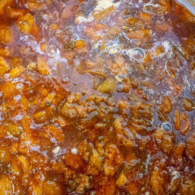 Büyük bir tencereye sıkıştır. Erik reçeli. Kayısı reçeli. Tencerede kayısı reçeli, yukarıdan görüntü. Ocaktaki tencerede kokulu portakal meyvesi ve köpük..