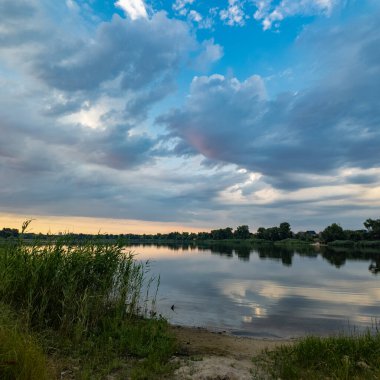 Çok güzel bir gün batımı ve su. Yaz akşamı manzarası. Sudaki bulutların yansıması. Güneş ufukta batıyor. Göllü yaz manzarası. Sudaki ağaçların yansıması. Nehirde gün doğumu. şehvetli bulutlar.