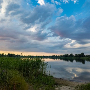 Çok güzel bir gün batımı ve su. Yaz akşamı manzarası. Sudaki bulutların yansıması. Güneş ufukta batıyor. Göllü yaz manzarası. Sudaki ağaçların yansıması. Nehirde gün doğumu. şehvetli bulutlar.