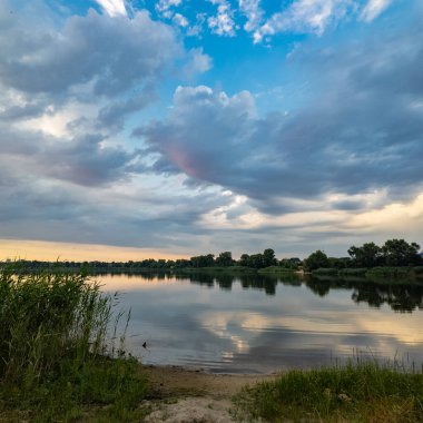 Çok güzel bir gün batımı ve su. Yaz akşamı manzarası. Sudaki bulutların yansıması. Güneş ufukta batıyor. Göllü yaz manzarası. Sudaki ağaçların yansıması. Nehirde gün doğumu. şehvetli bulutlar.