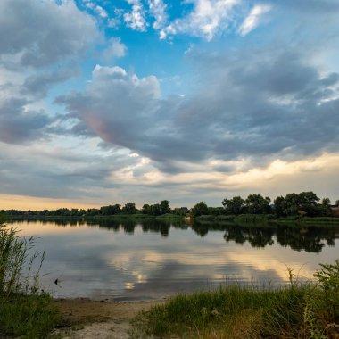 Çok güzel bir gün batımı ve su. Yaz akşamı manzarası. Sudaki bulutların yansıması. Güneş ufukta batıyor. Göllü yaz manzarası. Sudaki ağaçların yansıması. Nehirde gün doğumu. şehvetli bulutlar.