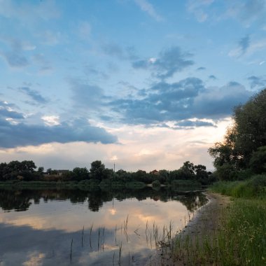 Çok güzel bir gün batımı ve su. Yaz akşamı manzarası. Sudaki bulutların yansıması. Güneş ufukta batıyor. Göllü yaz manzarası. Sudaki ağaçların yansıması. Nehirde gün doğumu. şehvetli bulutlar.