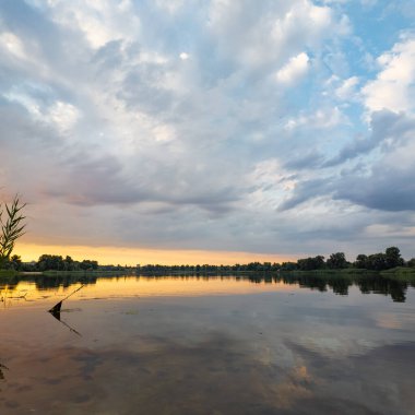 Çok güzel bir gün batımı ve su. Yaz akşamı manzarası. Sudaki bulutların yansıması. Güneş ufukta batıyor. Göllü yaz manzarası. Sudaki ağaçların yansıması. Nehirde gün doğumu. şehvetli bulutlar.