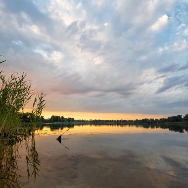 Çok güzel bir gün batımı ve su. Yaz akşamı manzarası. Sudaki bulutların yansıması. Güneş ufukta batıyor. Göllü yaz manzarası. Sudaki ağaçların yansıması. Nehirde gün doğumu. şehvetli bulutlar.