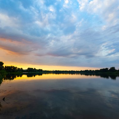 Çok güzel bir gün batımı ve su. Yaz akşamı manzarası. Sudaki bulutların yansıması. Güneş ufukta batıyor. Göllü yaz manzarası. Sudaki ağaçların yansıması. Nehirde gün doğumu. şehvetli bulutlar.