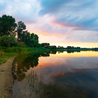 Çok güzel bir gün batımı ve su. Yaz akşamı manzarası. Sudaki bulutların yansıması. Güneş ufukta batıyor. Göllü yaz manzarası. Sudaki ağaçların yansıması. Nehirde gün doğumu. şehvetli bulutlar.