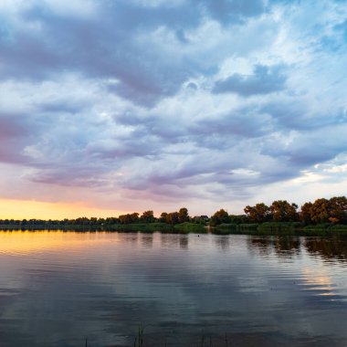 Çok güzel bir gün batımı ve su. Yaz akşamı manzarası. Sudaki bulutların yansıması. Güneş ufukta batıyor. Göllü yaz manzarası. Sudaki ağaçların yansıması. Nehirde gün doğumu. şehvetli bulutlar.