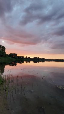 Çok güzel bir gün batımı ve su. Yaz akşamı manzarası. Sudaki bulutların yansıması. Güneş ufukta batıyor. Göllü yaz manzarası. Sudaki ağaçların yansıması. Nehirde gün doğumu. şehvetli bulutlar.