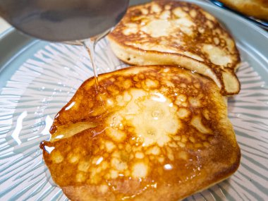 gözleme ve bal şurubu gümüş şuruplu sürahinin üstüne dökülür. Gri tabakta ev yapımı krepler ince bir yavaş çekim akışıyla servis edilir tatlım. Ortam planı.