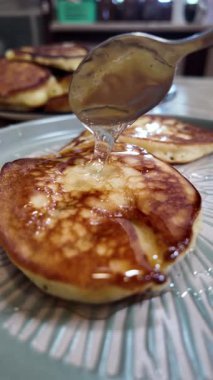 gözleme ve bal şurubu gümüş şuruplu sürahinin üstüne dökülür. Gri tabakta ev yapımı krepler ince bir yavaş çekim akışıyla servis edilir tatlım. Ortam planı.