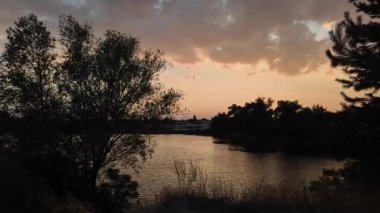 Suyun üstünde gün batımı. Kırmızı günbatımı güneşi. 4K video ve 24 FPS. Gölde gün doğumu. Nehir ve güneş. Doğal arka plan. Rüzgar ve su. Fırtınadan önce hava. Ukrayna manzarası. Dinyeper Nehri. su sörfü