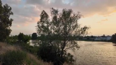 Suyun üstünde gün batımı. Kırmızı günbatımı güneşi. 4K video ve 24 FPS. Gölde gün doğumu. Nehir ve güneş. Doğal arka plan. Rüzgar ve su. Fırtınadan önce hava. Ukrayna manzarası. Dinyeper Nehri. su sörfü