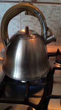 Ocakta ıslık çalan çaydanlık. Gaz ocağındaki su ısıtıcısı. Çaydanlıkta kaynamış bir adam. Parlak metal çaydanlık.