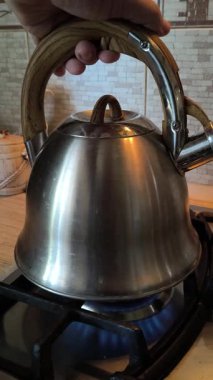 Ocakta ıslık çalan çaydanlık. Gaz ocağındaki su ısıtıcısı. Çaydanlıkta kaynamış bir adam. Parlak metal çaydanlık.