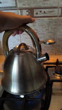 Ocakta ıslık çalan çaydanlık. Gaz ocağındaki su ısıtıcısı. Çaydanlıkta kaynamış bir adam. Parlak metal çaydanlık.