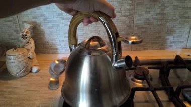 Ocakta ıslık çalan çaydanlık. Gaz ocağındaki su ısıtıcısı. Çaydanlıkta kaynamış bir adam. Parlak metal çaydanlık.