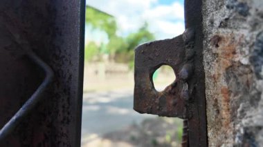 Eski paslı demir kapı. Eski kilit. Kapıda paslı bir kilit var. Paslı demir, sahil etrafında enkaz olan evler, sel basmış yerleşim alanları.