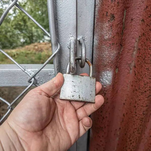 Eski asma kilit. Adam eski metal kilidi açıyor. Eski evdeki ahşap kapı. Dükkanını asma kilit ve metal kepenkle kapatan bir adam. Yakın plan. 4K Çözünürlüğü.