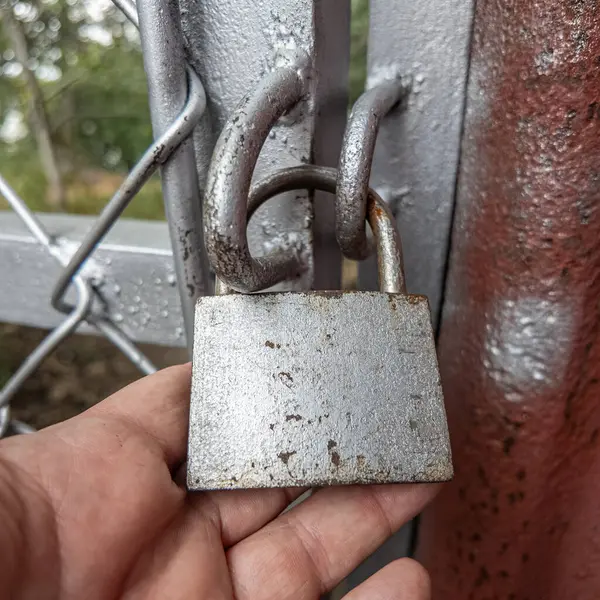 Eski asma kilit. Adam eski metal kilidi açıyor. Eski evdeki ahşap kapı. Dükkanını asma kilit ve metal kepenkle kapatan bir adam. Yakın plan. 4K Çözünürlüğü.