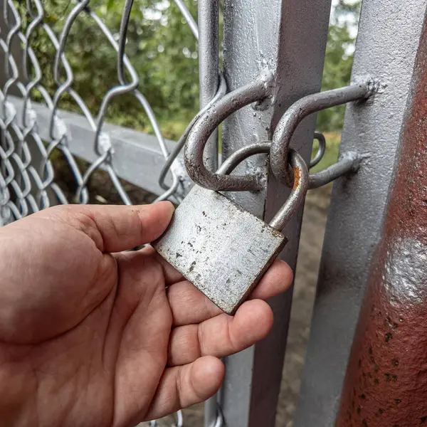 Eski asma kilit. Adam eski metal kilidi açıyor. Eski evdeki ahşap kapı. Dükkanını asma kilit ve metal kepenkle kapatan bir adam. Yakın plan. 4K Çözünürlüğü.