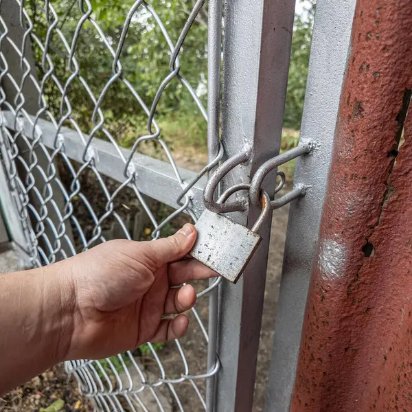 Eski asma kilit. Adam eski metal kilidi açıyor. Eski evdeki ahşap kapı. Dükkanını asma kilit ve metal kepenkle kapatan bir adam. Yakın plan. 4K Çözünürlüğü.