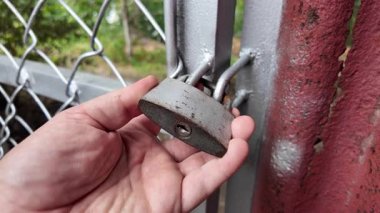 Eski asma kilit. Adam eski metal kilidi açıyor. Eski evdeki ahşap kapı. Dükkanını asma kilit ve metal kepenkle kapatan bir adam. Yakın plan. 4K Çözünürlüğü.