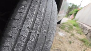 Çok yıpranmış araba lastikleri. Yakın plan bir arabanın eski lastikleri. Yoldaki çukurlarla kaplı hasarlı bir otoyolda giden araç lastiği. POV kamerası yana bağlandı