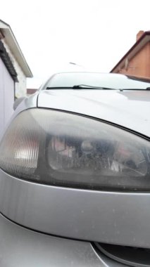 Eski araba farları. Yansıtıcı far. Halojen ışığı. Eski bir SUV 'nin yakın plan farı. Kirli far ve beyaz bir otomobilin tamponu..