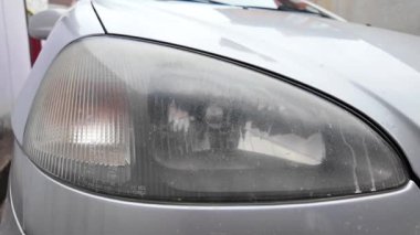 Eski araba farları. Yansıtıcı far. Halojen ışığı. Eski bir SUV 'nin yakın plan farı. Kirli far ve beyaz bir otomobilin tamponu..