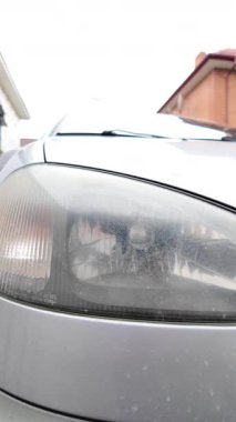 Eski araba farları. Yansıtıcı far. Halojen ışığı. Eski bir SUV 'nin yakın plan farı. Kirli far ve beyaz bir otomobilin tamponu..