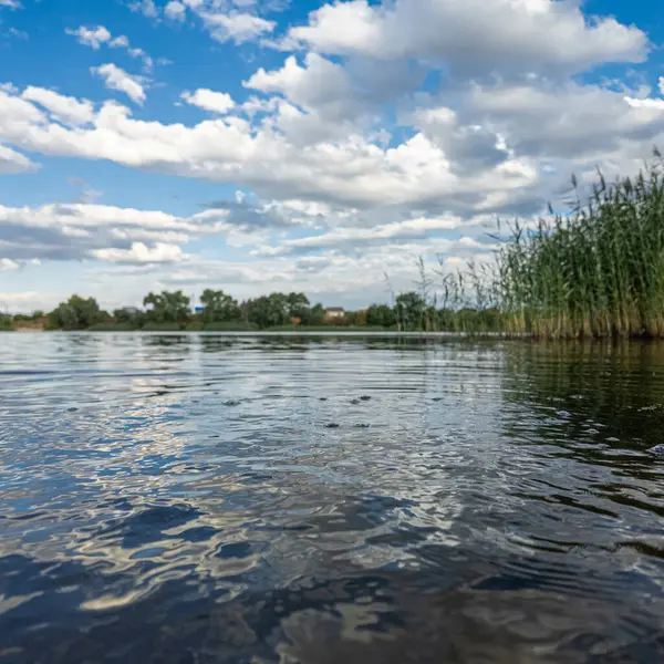 Göldeki suyun yavaş çekim videosu. Dalgalar yavaş çekimde köpük saçıyor. Sıcak gün batımının yüzeydeki yansımaları ile çekilen sakin su hareketi.