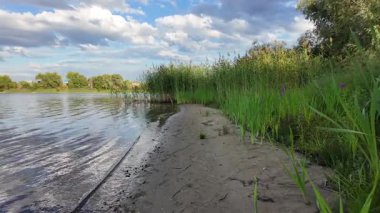 Bulutlar suda yansıyor. Gökyüzü ve nehir. Göllü doğal manzara. Göl üzerinde yağmur bulutları. Nehirdeki pürüzsüz karanlık su. Yavaş çekim video doğal manzara. Doğa geçmişi. 4k çözünürlüğü