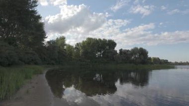 Bulutlar suda yansıyor. Gökyüzü ve nehir. Göllü doğal manzara. Göl üzerinde yağmur bulutları. Nehirdeki pürüzsüz karanlık su. Yavaş çekim video doğal manzara. Doğa geçmişi. 4k çözünürlüğü