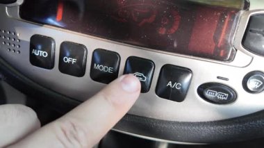 Analog araba düğmeleri. Klasik teypte parmak oynatma düğmesine basan adam. Aydınlatılırken klimayı devre dışı bırakmak için parmak kapatma düğmesine basın