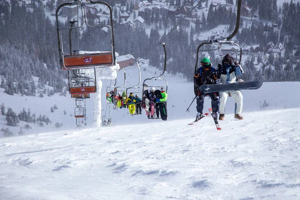 Kayakçılar ve snowboardcular Karpatlar 'daki Dragobrat Dağı' nın tepesine asansörle tırmanırlar.