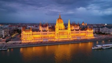 Macaristan 'ın Budapeşte kentinde günbatımından sonra Tuna Nehri ile Macar Parlamento Binası' nı aydınlattı. 4K hava aracı görüntüsü