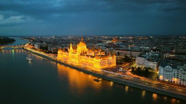 Macaristan 'ın Budapeşte kentinde günbatımından sonra Tuna Nehri ile Macar Parlamento Binası' nı aydınlattı. 4K hava aracı görüntüsü