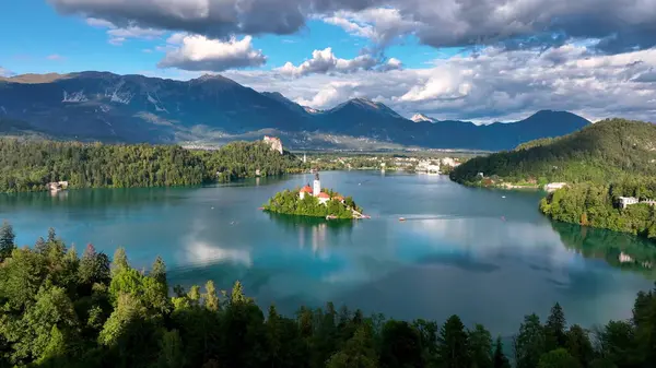湖の上のマリア被昇天巡礼教会の周りを飛行する4Kの空中映像雲で美しい秋の日に祝福されました スロベニアのブレッド湖 — ストック写真