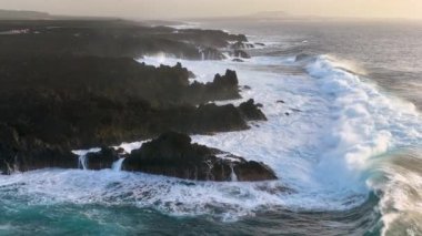 Gök mavisi okyanusun 4K yavaş çekim görüntüsü ve kayalık kayalıklara çarpan dev dalgalar. Lanzarote. Kanarya Adaları, İspanya