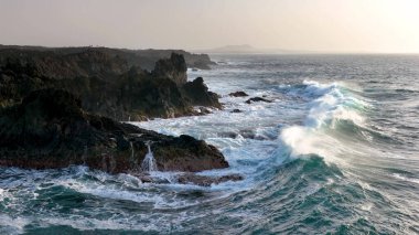 Gök mavisi okyanusun 4K yavaş çekim görüntüsü ve kayalık kayalıklara çarpan dev dalgalar. Lanzarote. Kanarya Adaları, İspanya