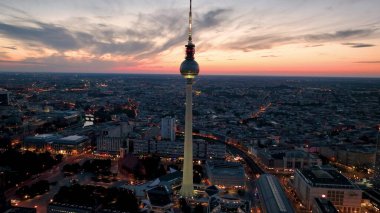Hava videosu, görkemli bir kuleye sahip canlı bir şehir manzarası gösteriyor. Ünlü mimari mekanlar, TV Kulesi, Alexanderplatz geceleri. Berlin, Almanya