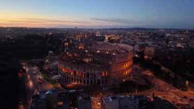 Kolezyum 'un 4k Aerial View' ı alacakaranlıkta görkemli bir şekilde duruyor. Antik taşı, canlı günbatımının gökyüzü ve Roman şehri boyunca renkler saçarak çevreyi aydınlattığı gibi sıcak bir şekilde parlıyor. İtalya