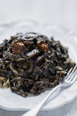    close up of plate of squid ink tagliatelle pasta                            