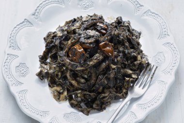    close up of plate of squid ink tagliatelle pasta                            