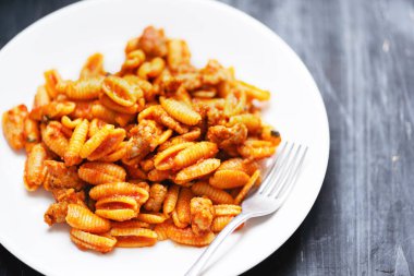 Bir tabak sosis soslu gnocchetti makarna.                            