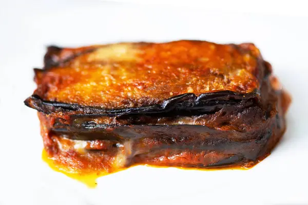 Close up of a plate of rustic italian eggplant parmigiana isolated