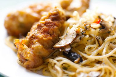 Bir tabak aglio olio makarna ve hırpalanmış balık.