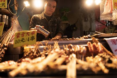 Guilin, Guangxi Eyaleti, Çin, 22 Ekim 2024, Guilin Food Caddesi her türlü yerel sokak yemeği için yoğun ve popülerdir. BBQ et adam lezzetli et şişleri pişiriyor..