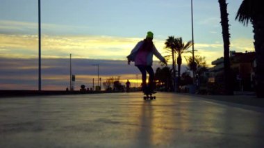 A girl rides a skateboard against the backdrop of a sunset. High quality 4k footage
