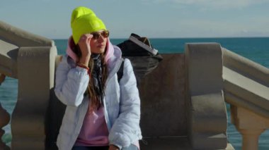 A girl sits on a stone bench. High quality 4k footage